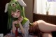 Anime girl with green hair and bunny ears laying on a bed.