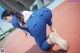 A woman in a blue uniform crouching down on a track.