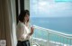 A woman standing on a balcony looking out at the ocean.