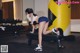 A woman doing dumbbell curls on a bench in a gym.