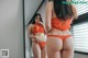 A woman in an orange lingerie standing in front of a mirror.