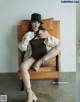 A woman sitting on a chair wearing a hat and boots.