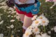 A woman in a field of daisies holding a bottle of water.