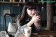 A woman sitting at a table with a cup of coffee and a cell phone.