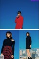 A woman in a red sweater and black dress standing on a balcony.