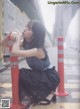 A woman sitting on the ground next to a red and white pole.