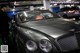 A man standing next to a car in a garage.