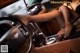 A woman sitting in the driver's seat of a car with her feet on the steering wheel.