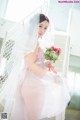 A woman in a wedding dress holding a bouquet of flowers.