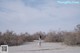 A woman in a white dress walking on a sandy beach.